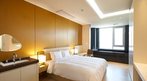 A bright and spacious deluxe hotel room with a king-sized bed and modern furniture.